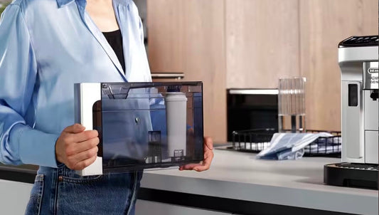 Person holding the water tank with an installed De'Longhi water filter for easy maintenance of a coffee machine, emphasizing proper coffee machine care. 